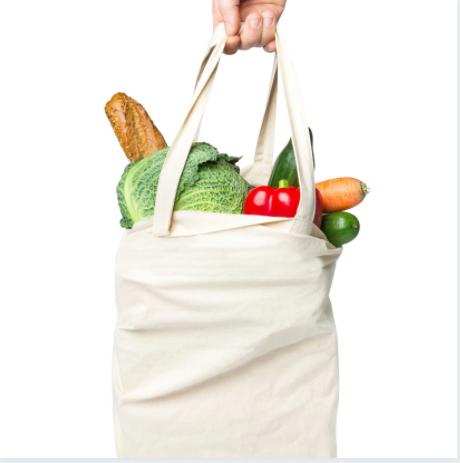 White cloth grocery bag filled with items including baguette, lettuce, red pepper and carrot.