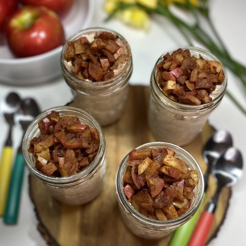 4 jars of apple pie overnight oats with apples and flowers in the background