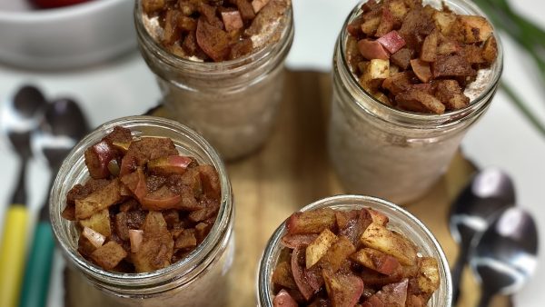 4 jars of apple pie overnight oats with apples and flowers in the background