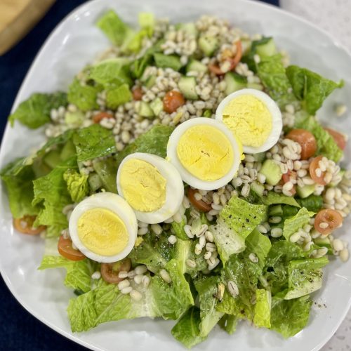 Salad with barley, lettuce, tomatoes, cucumber and hard cooked egg