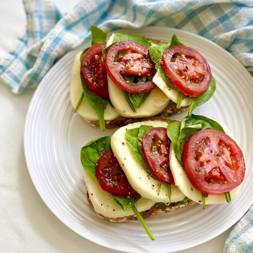 Tomatoes, cheese, spinach and basil on avocado toast