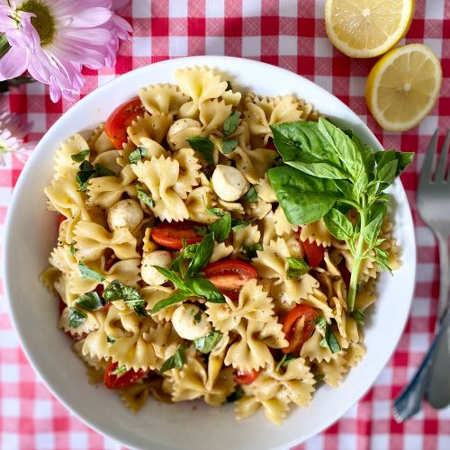 Bowl of bowtie pasta salad with mini bocconcini cheese and tomatoes.