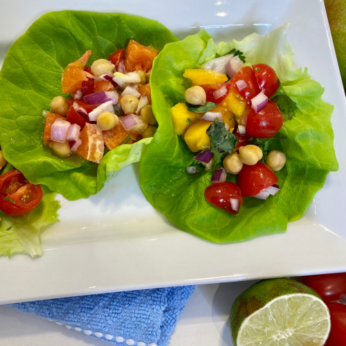 Two lettuce leaves each filled with a mixture of chickpeas, mango, tomatoes and onions .