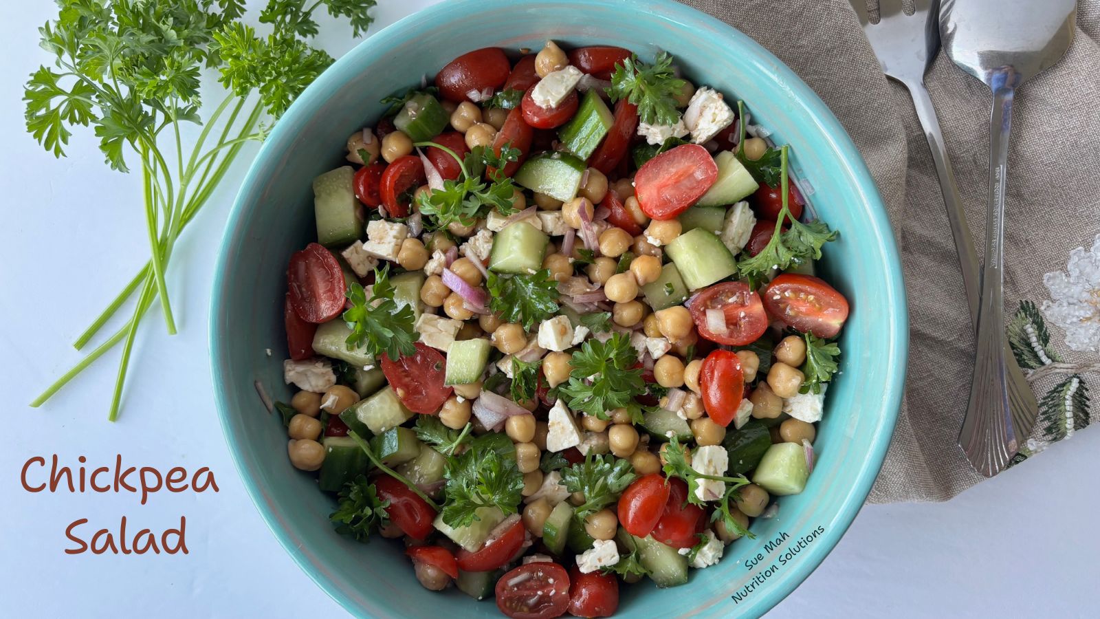 A bowl with chickpeas, feta cheese, tomatoes, cucumbers and parsley