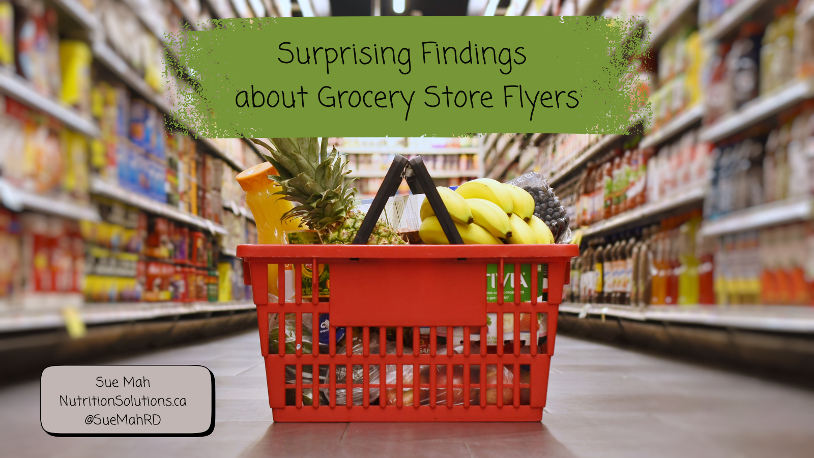 A red grocery basket filled with foods in a grocery store aisle