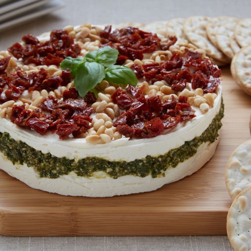 A beautiful plate of Basil Pesto Torte topped with pine nuts and sun-dried tomatoes.