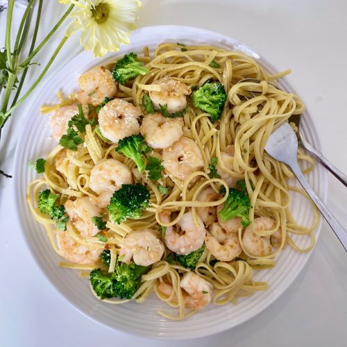 A plate of shrimp linguine with broccoli florets.
