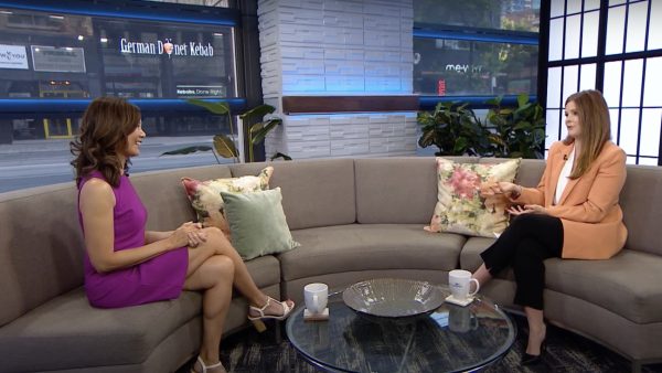 Sue Mah is sitting on a sofa in TV studio and chatting with host LIndsey Deluce