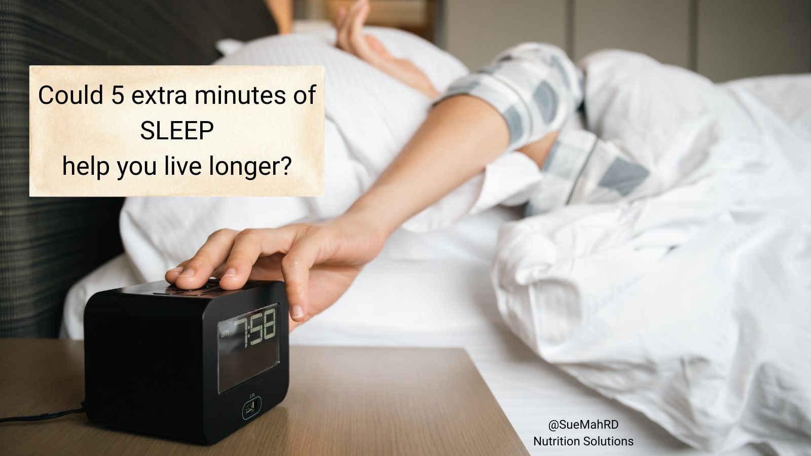 A person sleeping and reaching for alarm clock