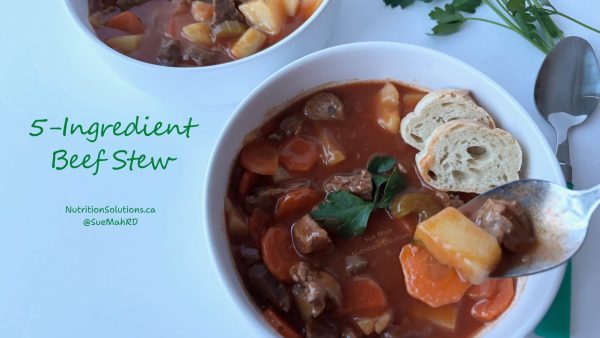Two bowls of beef stew with carrots, potatoes and a couple of pieces of bread in the bowl.