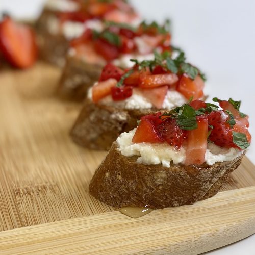 Strawberry bruschetta appetizers on a wooden cutting board